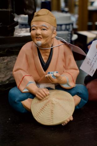1950s Hakata Urasaki figure eating rice, holding hat