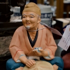 1950s Hakata Urasaki figure eating rice, holding hat